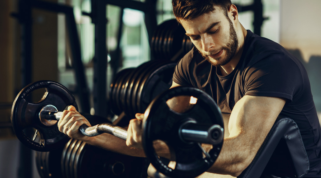 Bearded man working out his biceps and forearms with a preacher curl exercise