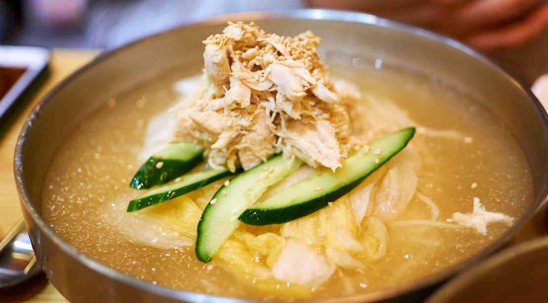 Shredded chicken soup garnished with cucumbers