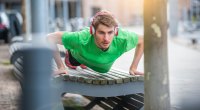 Jeune Homme Sportif Avec Des Écouteurs Faisant Des Pompes Sur Le Banc