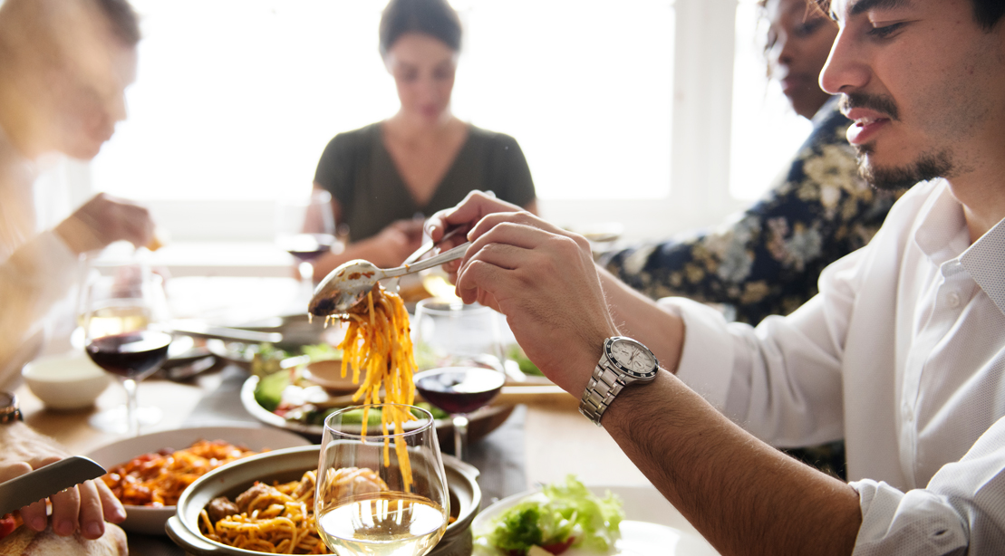 Group of friends eating a high carb meal serving pasta