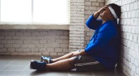 Overweight man frustrated and sitting on the floor against a gym wall