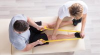 Physical-Therapist-Helping-Man-With-Banded-Row-Exercise
