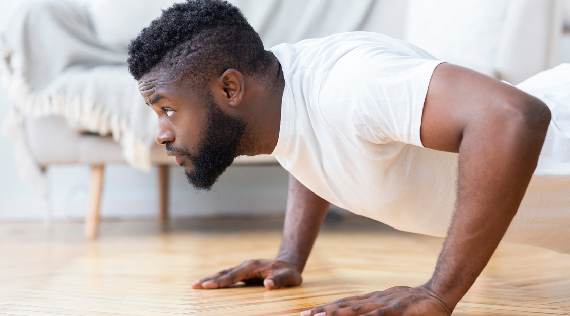 Young black man doing pushups in his bedroom