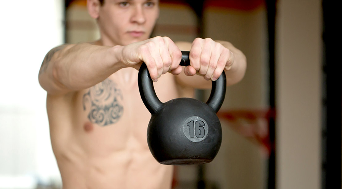 Young fitness model doing an upper body workout with a kettlebell exercise