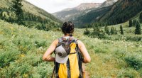 Female hiking through the mountains with a hat and bag