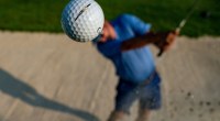 Golfer hitting the golf ball out of a sand bunker