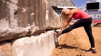 Female monster truck driver Kayla Blood doing leg stretches on the monster truck track and arena