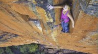 Female Rock Climber Sasha DiGiulian taking a break while climbing the side of a mountain